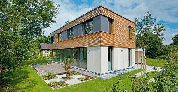 Nach Süden öffnet sich der Baukörper mit raumhohen Glasflächen zur Terrasse, im Obergeschoss sind die Fenster optisch zu einem Band zusammengefasst. Foto: Gruber Naturholzhaus