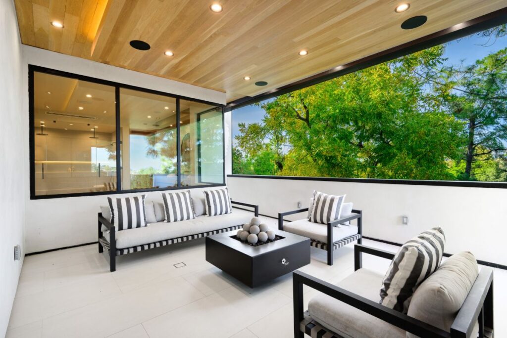 Eine überdachte Veranda mit Sitzbereich und Fenstern, Wohnraum im Freien.