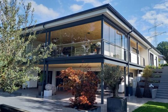 Lehner Haus individueller Bungalow am Hang Ansicht seitlich mit Glasfront und Garten mit Steintreppe