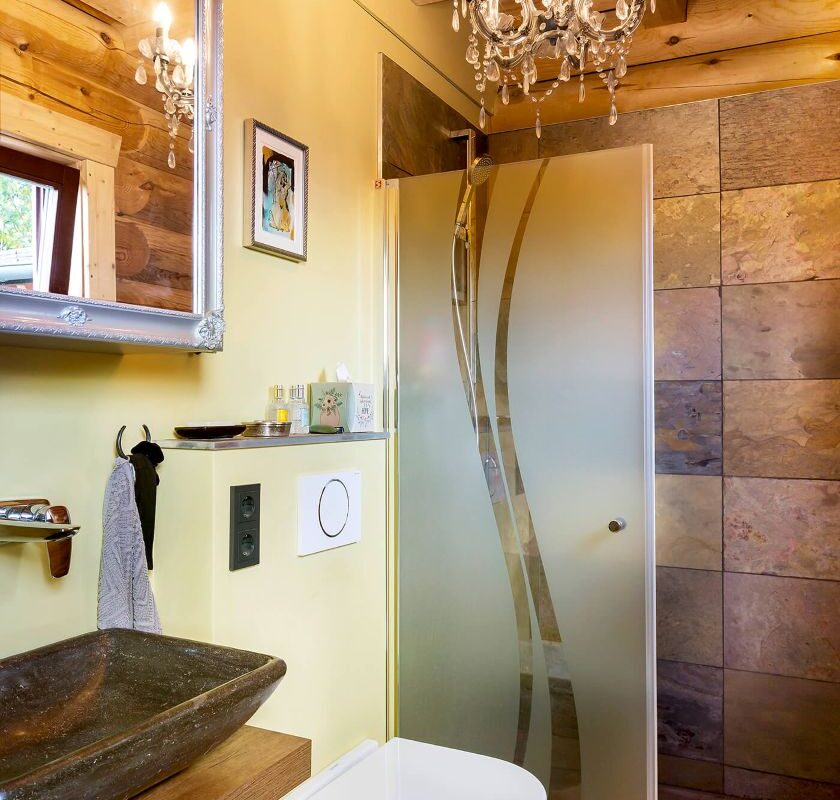 LéonWood Blockhaus Husky Badezimmer mit Holzwänden und Kronleuchter