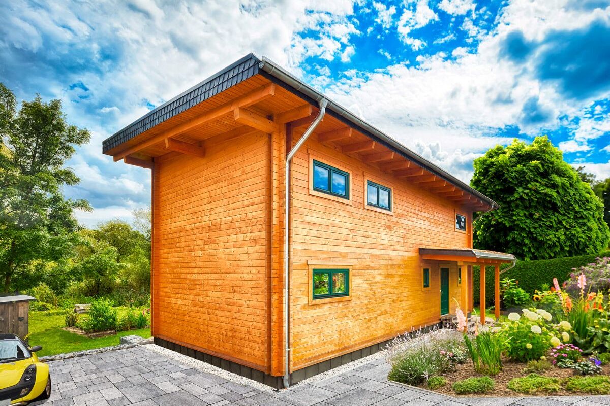 Blockhaus Alpina One Einfahrt und Hauseingang mit Garten